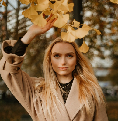 Woman photographed beneath golden autumn leaves